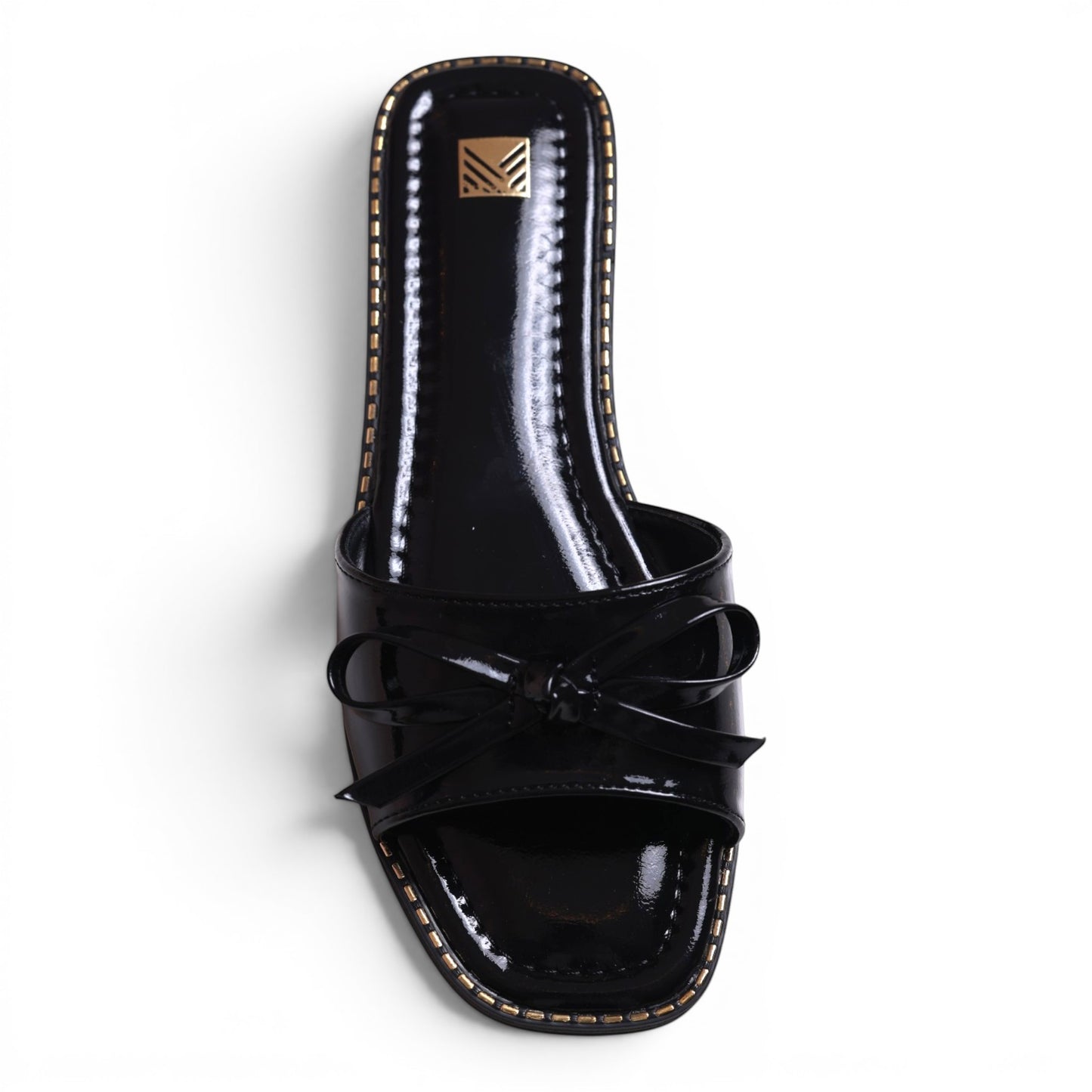 Moda Ug black patent leather slide sandals with bow detail and gold trim. Square toe.