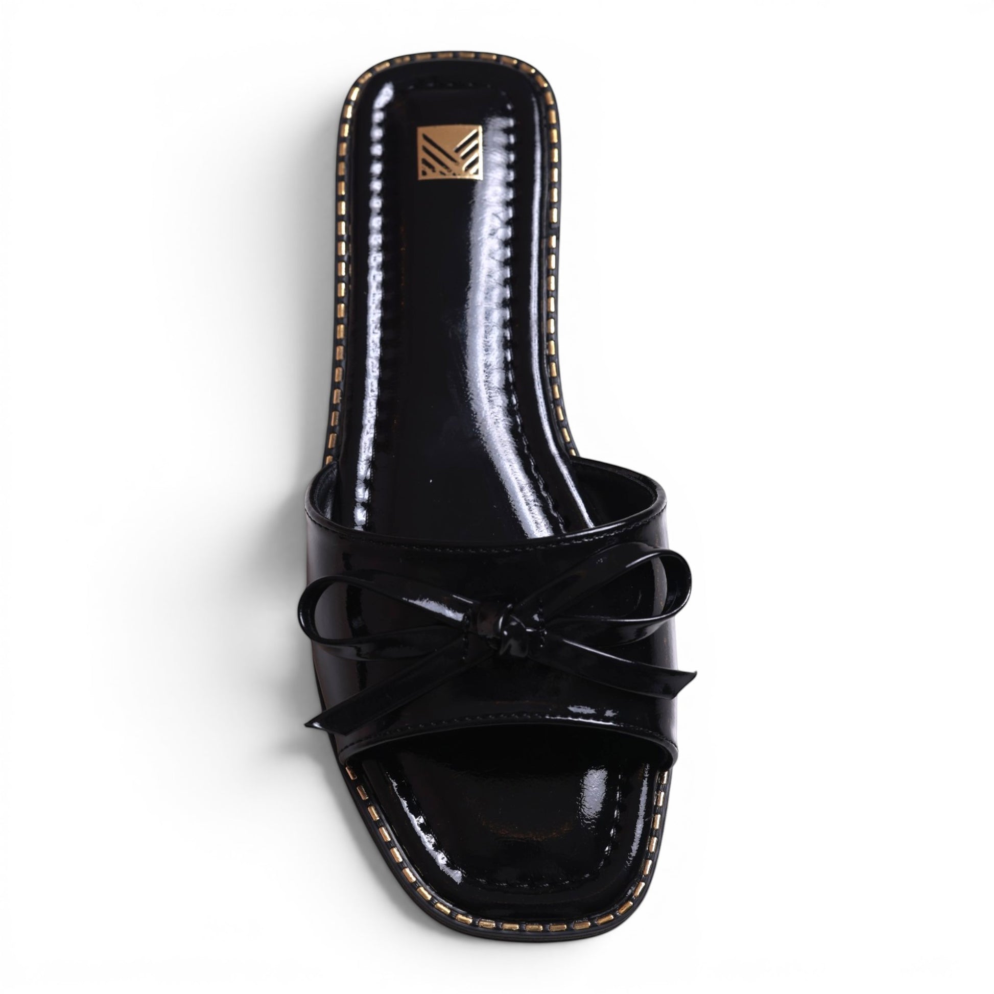 Moda Ug black patent leather slide sandals with bow detail and gold trim. Square toe.