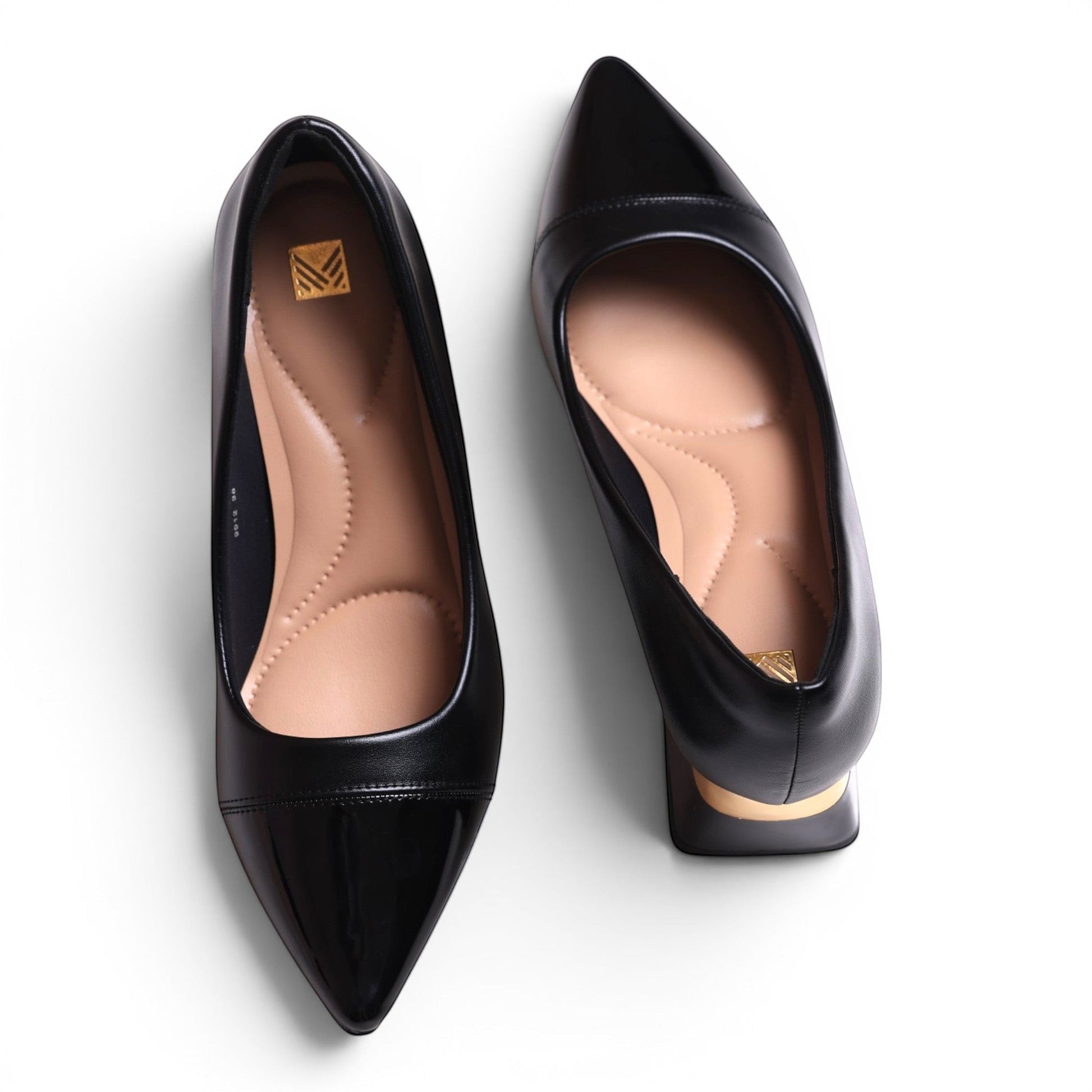 Moda Ug black pointed-toe pumps with a patent cap toe and cushioned insole. Features a low block heel with gold accent.
