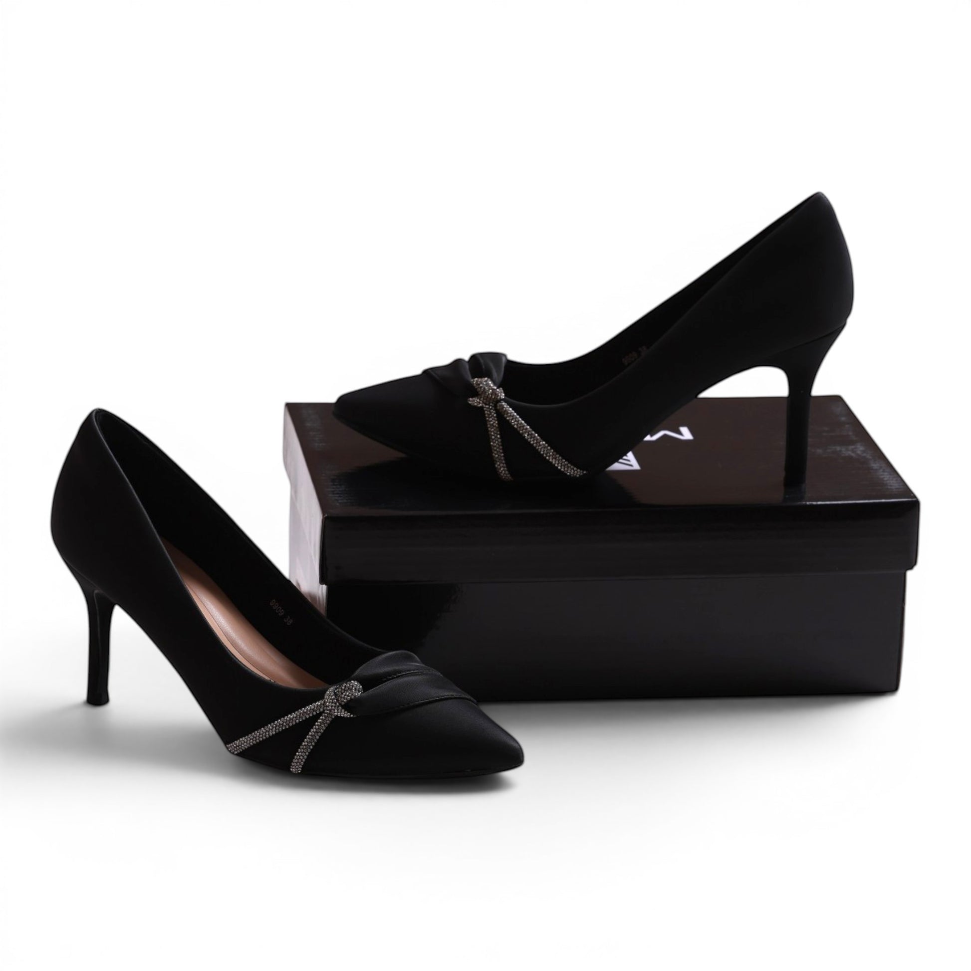 Moda Ug black satin pointed-toe pumps with crystal bow detail and stiletto heel.