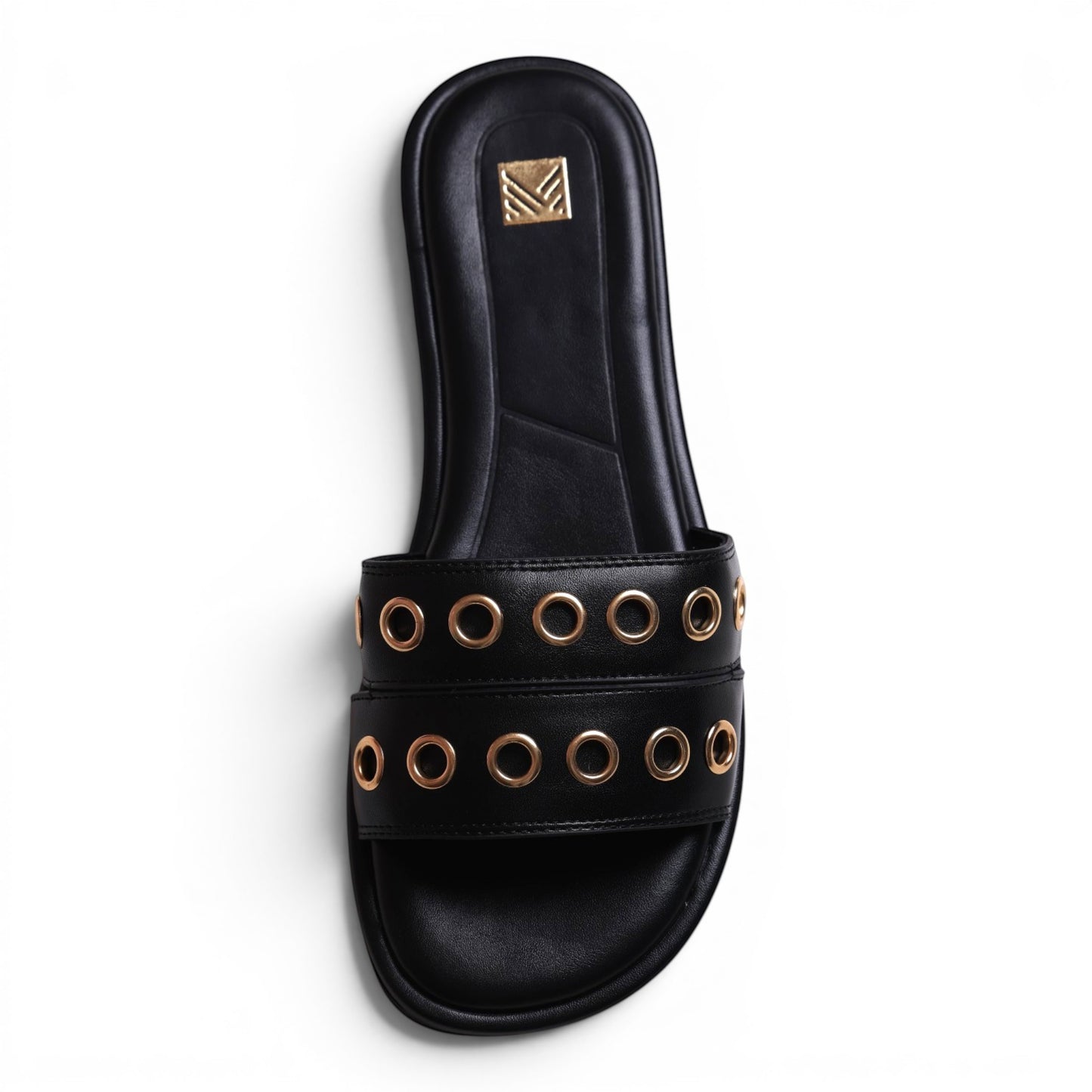 Moda Ug black leather slide sandals with gold eyelet detailing and a gold logo emblem on the strap.
