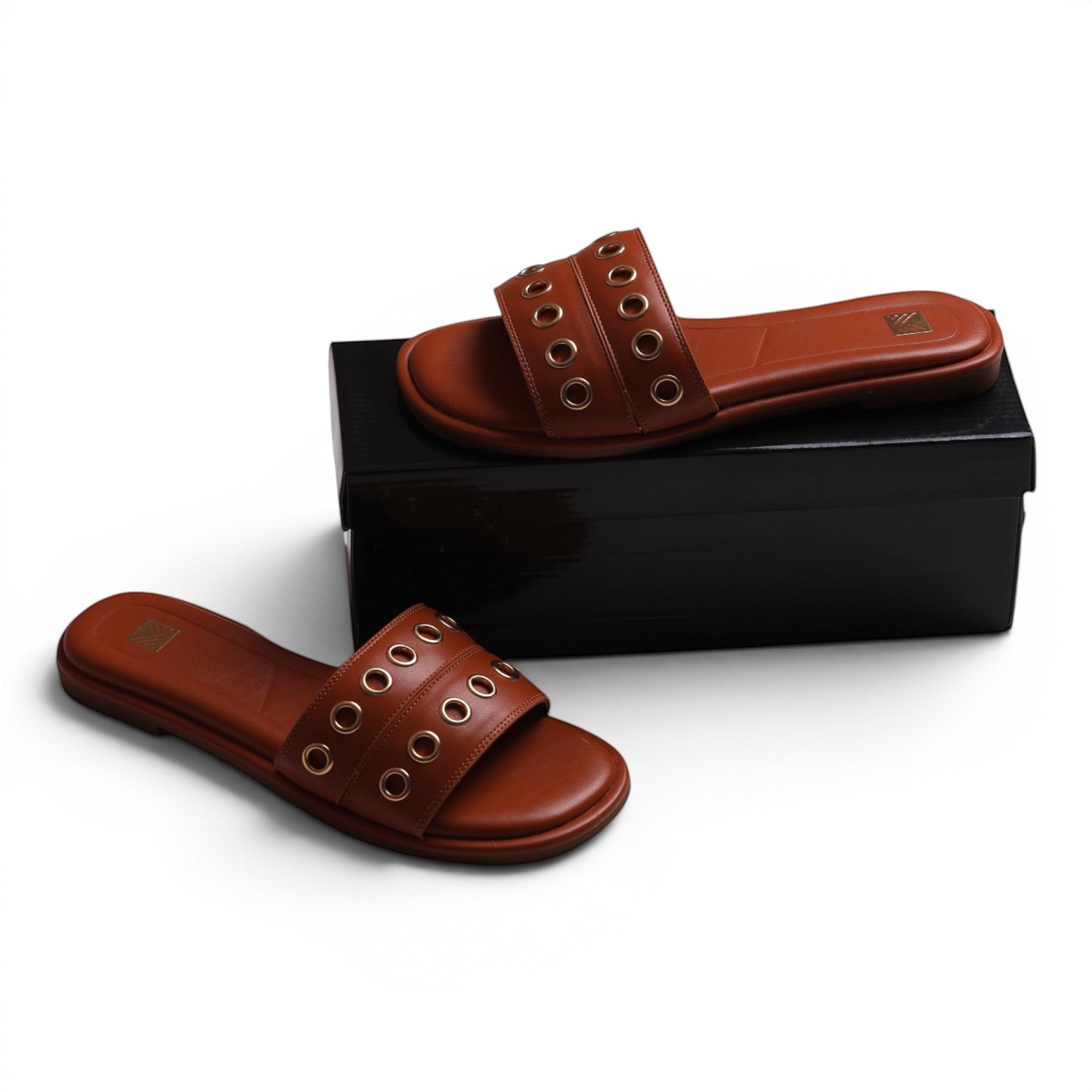 Moda Ug brown leather slide sandals with gold eyelet details and a flat sole.