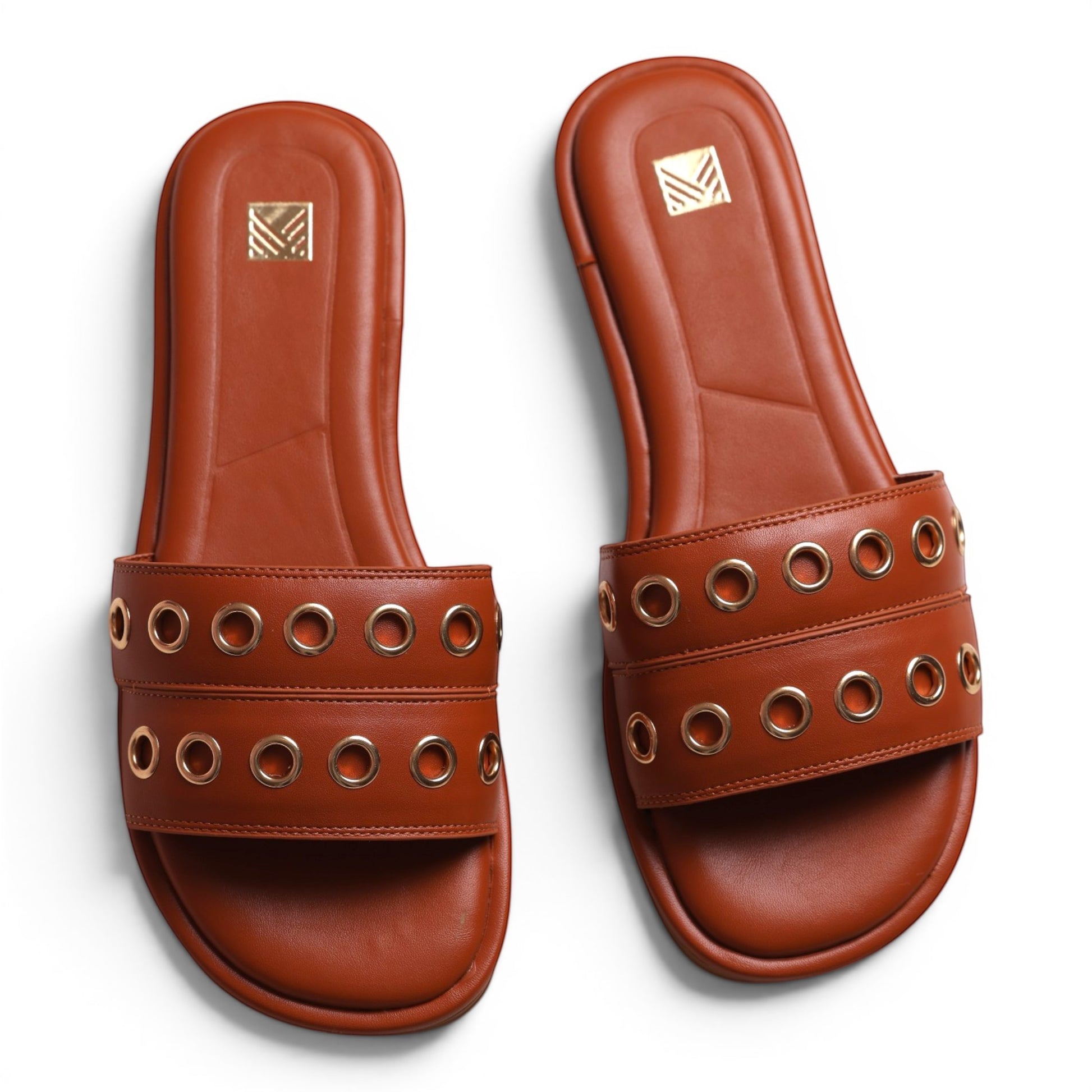 Moda Ug brown leather slide sandals with gold eyelet details and cushioned footbed.