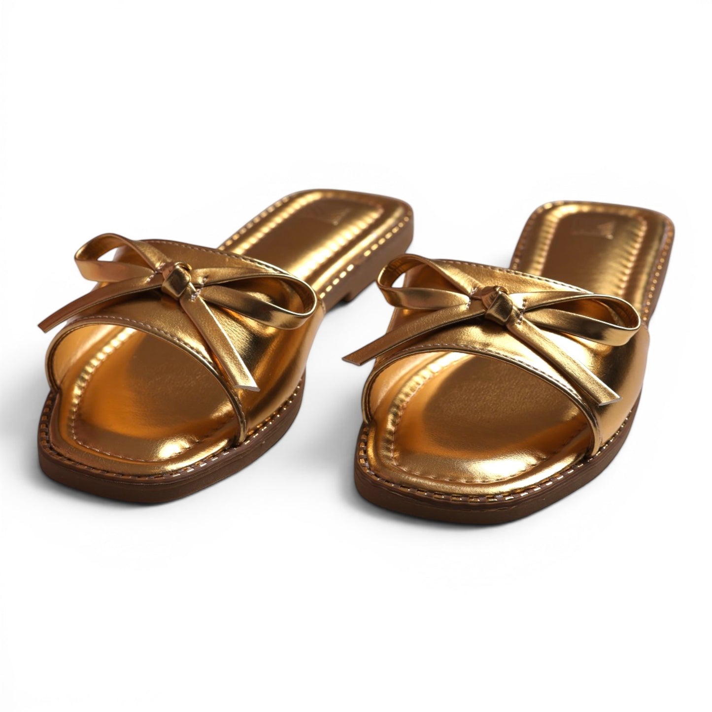 Moda Ug gold metallic slide sandals with bow detail. Open-toe, slip-on style.