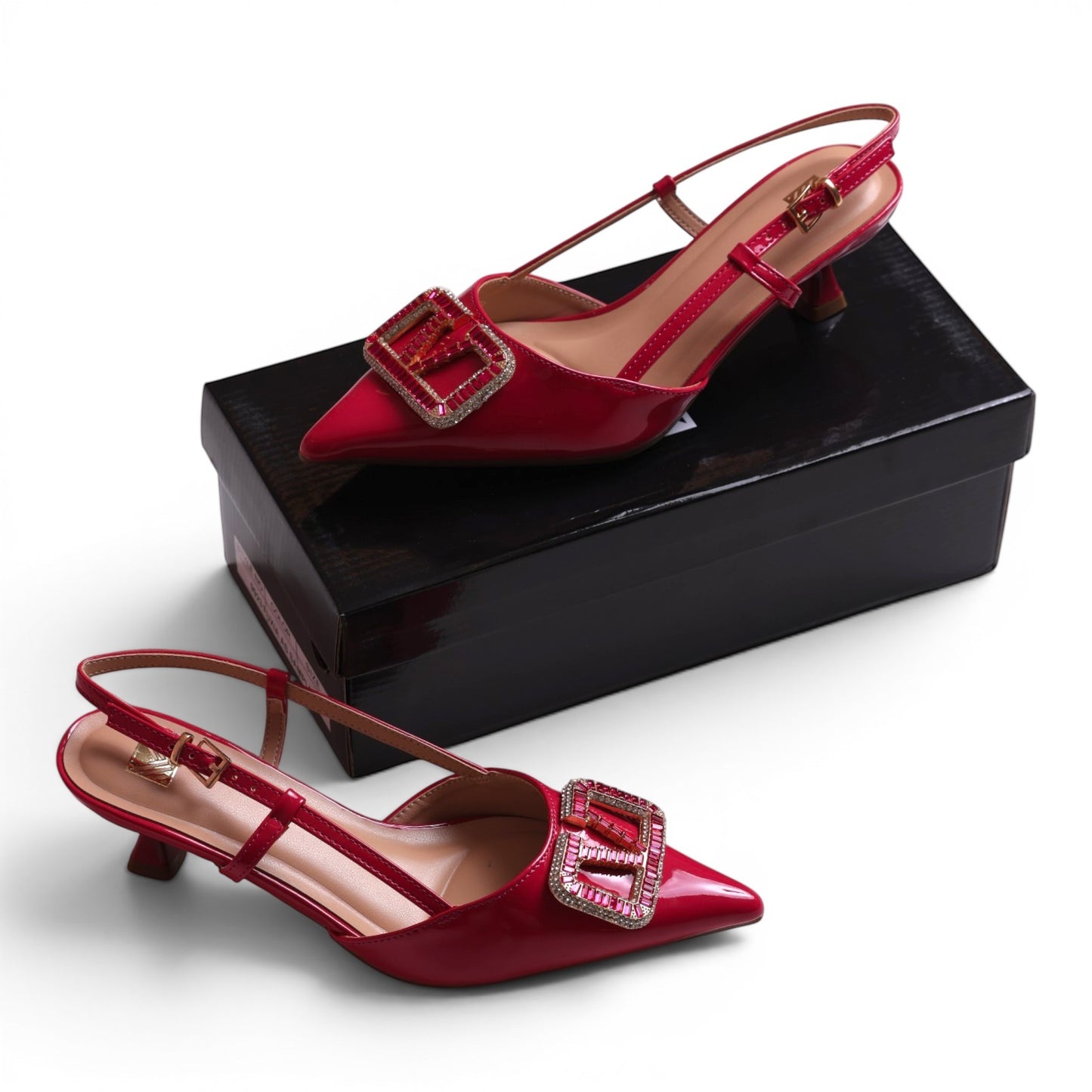 Moda Ug red patent leather slingback heels with a decorative jeweled buckle and adjustable ankle strap.