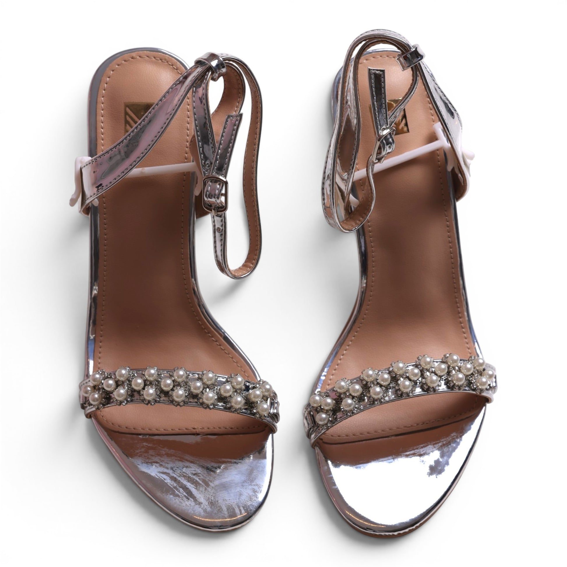Moda Ug silver metallic heeled sandals with pearl and rhinestone embellishments on the strap and ankle strap.