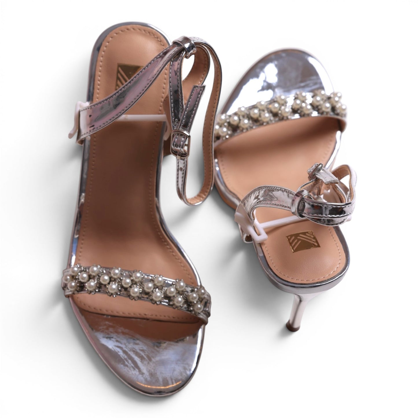 Moda Ug silver metallic heeled sandals with pearl and rhinestone embellishments on the strap.